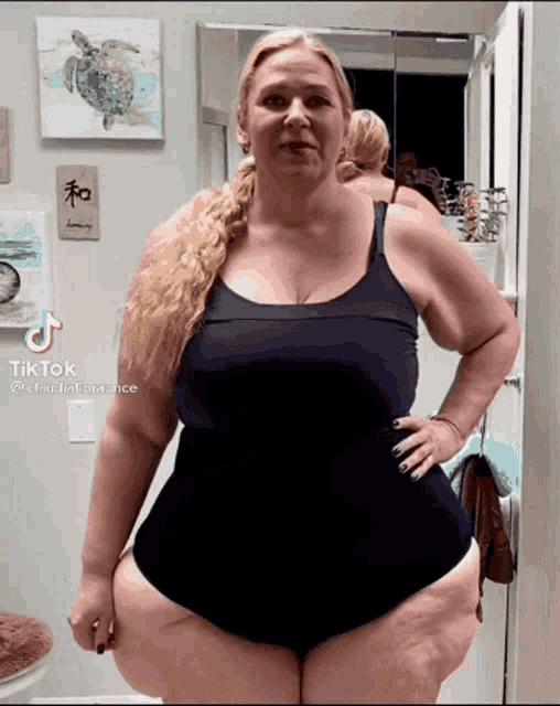 a woman is standing in front of a mirror with her hands on her hips .