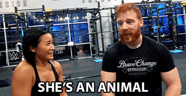 a man and a woman are in a gym and the man is wearing a brave change gymnasium shirt