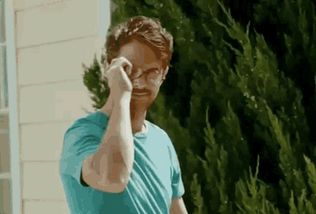 a man wearing glasses is standing in front of a house