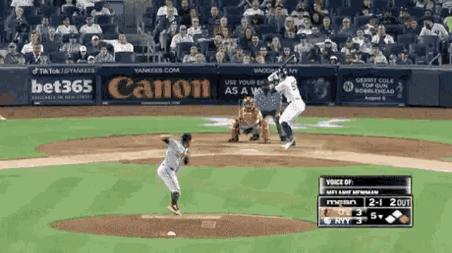 a baseball game is being played in a stadium with advertisements for canon and bet365 on the wall .