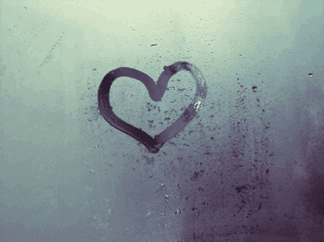 a heart is drawn on a window with rain drops