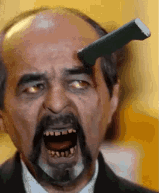 a bald man with a beard is holding a knife to his forehead