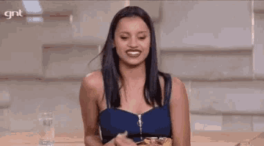 a woman is laughing while holding a bag of chips in her hand .