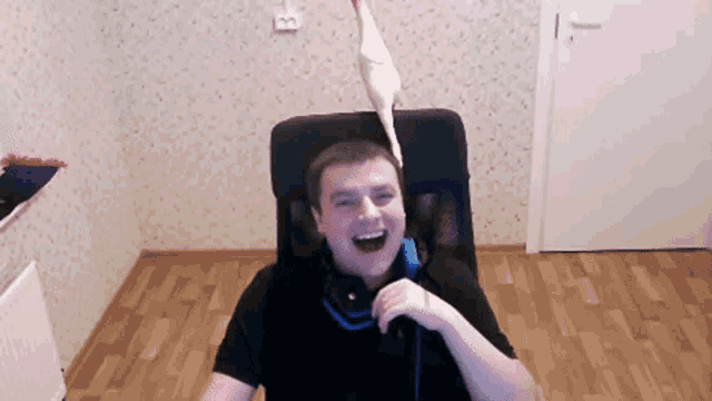 a man is sitting in a chair with a bird on his head