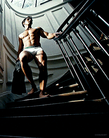 a shirtless man in calvin klein underwear is walking down a set of stairs