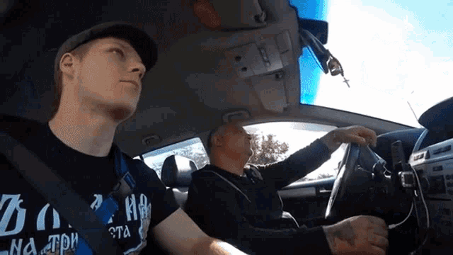 a man wearing a t-shirt that says do no trip is driving a car with another man