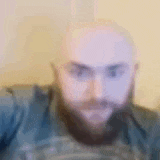 a bald man with a beard is looking at the camera in a blurry picture .