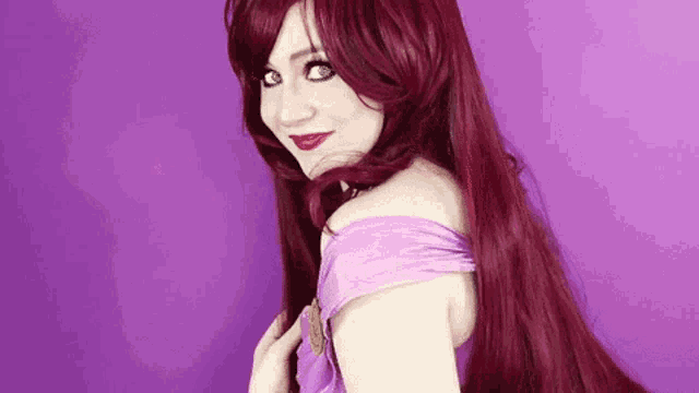 a woman with long red hair is wearing a purple dress and red wig .