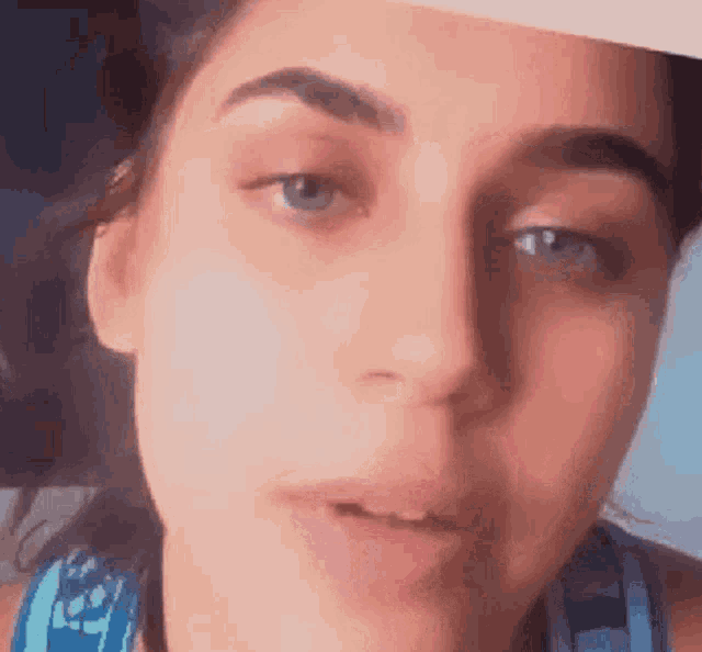a close up of a woman 's face with a blue tank top on
