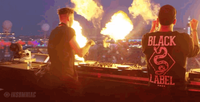 a man in a black label shirt stands in front of a fire