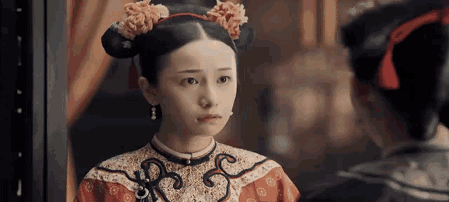 a woman in a traditional costume is looking at herself in the mirror