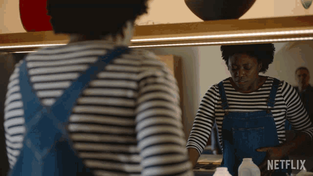 a woman in overalls is looking at herself in a mirror with netflix written on the bottom right