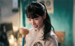 a woman in a white jacket is holding a rubber mallet in her hand .