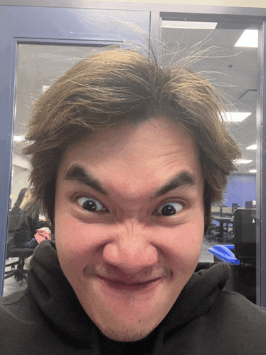 a man is making a funny face in front of a glass door