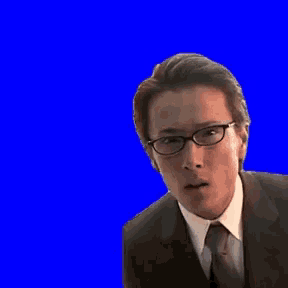 a man wearing glasses and a suit is making a funny face against a blue background