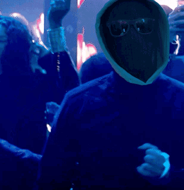 a man wearing sunglasses and a mask is dancing in front of a crowd