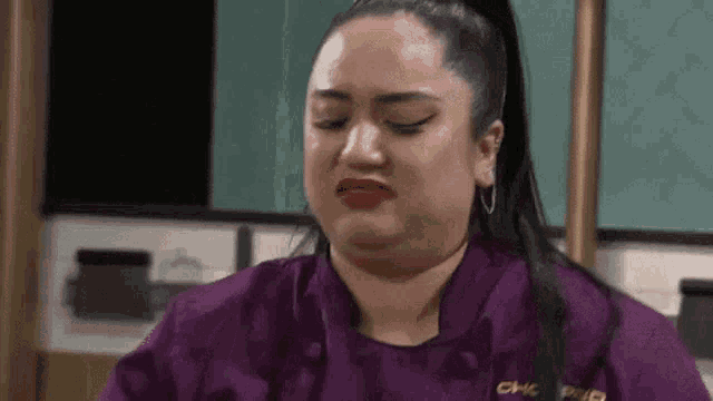 a woman in a purple chef 's jacket is crying .