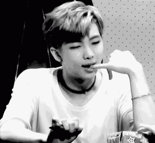 a black and white photo of a young man eating something .