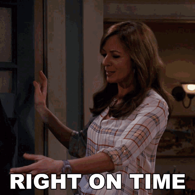 a woman in a plaid shirt is standing in front of a door with the words right on time behind her