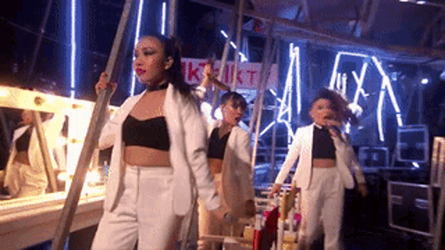 a group of women in white suits are dancing in front of a sign that says ukt