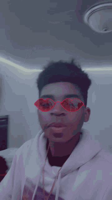 a young man wearing a purple hoodie and heart shaped sunglasses