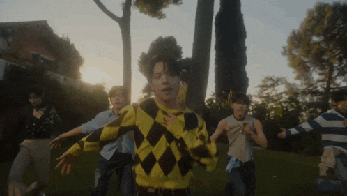 a man in a yellow and black sweater is surrounded by other men