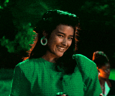 a woman wearing a green shirt and hoop earrings is smiling