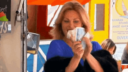 a woman is holding a bunch of money in her hands and smiling .