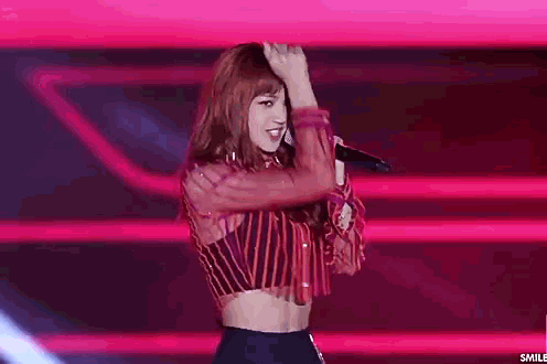 a woman in a striped shirt is holding a microphone on stage .