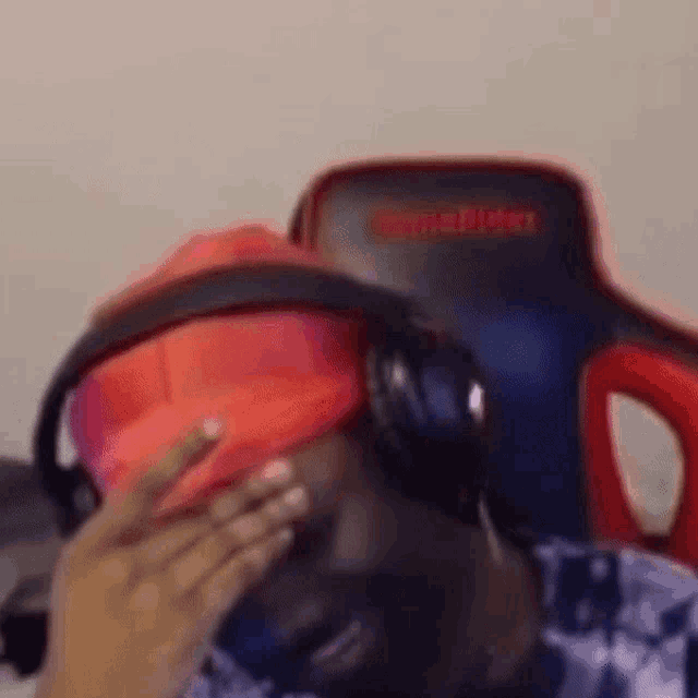 a man wearing a red hat and headphones is sitting in a chair .