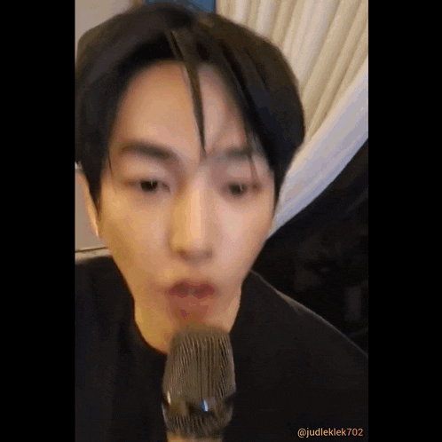 a man is singing into a microphone and making a face .