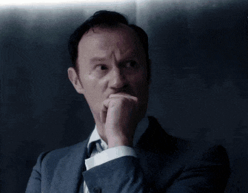 a man in a suit and tie is holding his hand to his chin