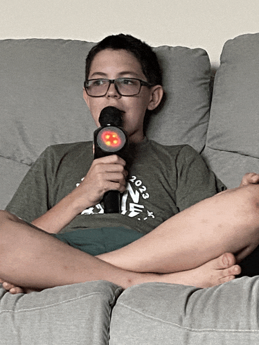 a boy sitting on a couch holding a microphone with the year 2020 on it