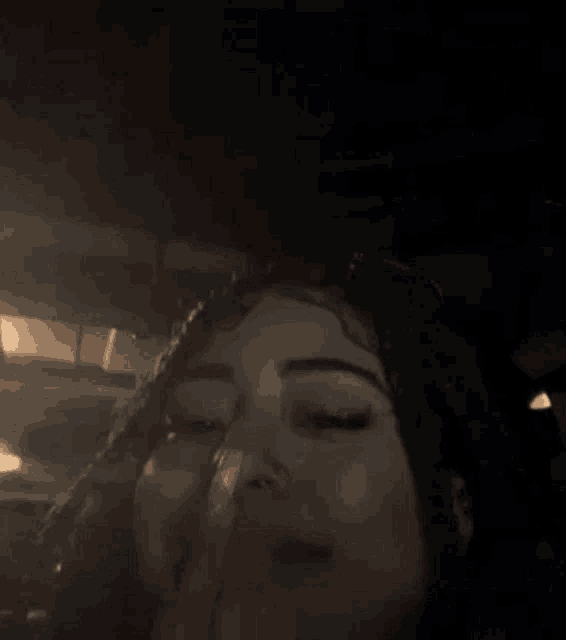 a close up of a woman 's face with her eyes closed and a finger in her nose .