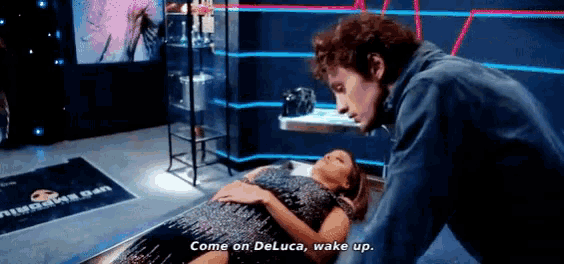 a man is standing next to a woman laying on a bed and says come on deluca wake up .
