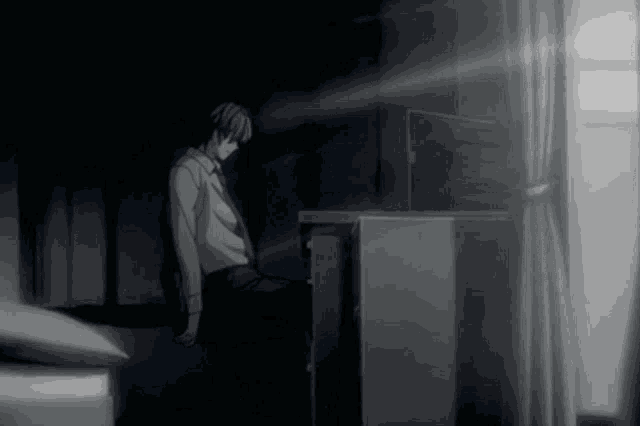 a man in a suit and tie is sitting at a desk in the dark .