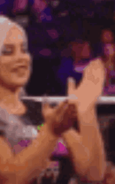 a blurry picture of a woman clapping her hands in a crowd