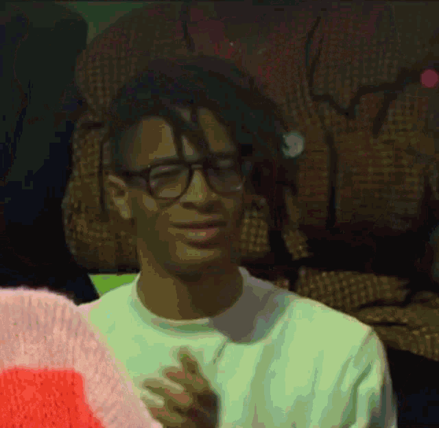 a man wearing glasses and a pink sweater looks at the camera