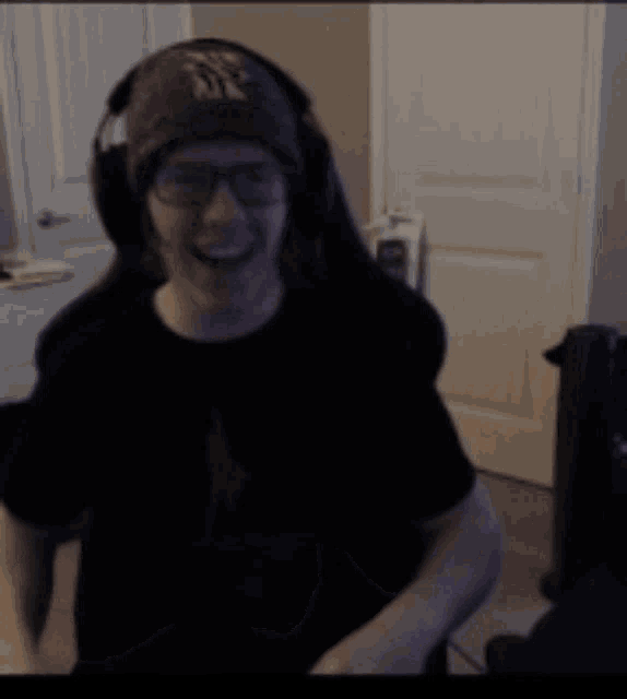 a man wearing headphones and a hat is dancing in a room .