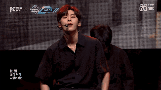 a man singing into a microphone with the words we are k pop behind him