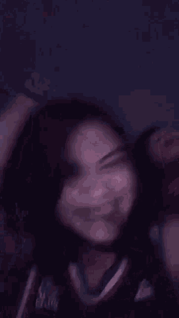 a woman is smiling and dancing in a dark room while a man holds her hand .