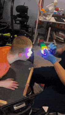 a person wearing blue gloves is holding a rainbow colored object in front of a child 's face
