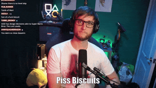 a man wearing glasses and headphones stands in front of a microphone and says " piss biscuits "