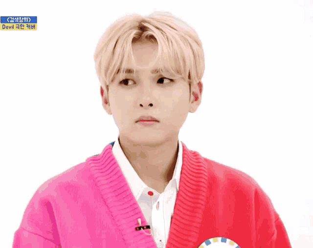 a young man wearing a pink sweater and a white shirt with devil written on it