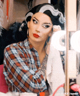 a woman in a plaid shirt is looking at herself in a mirror