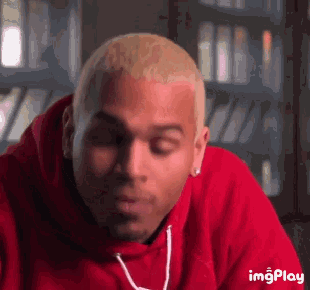 chris brown is wearing a red hoodie and earring .