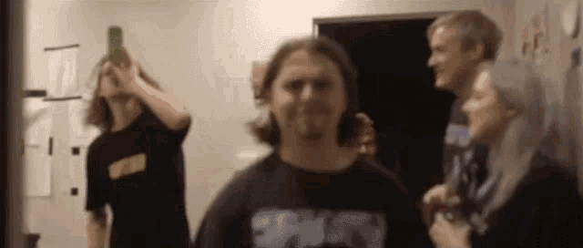a group of people are standing in a room and a man is holding a bottle of beer .