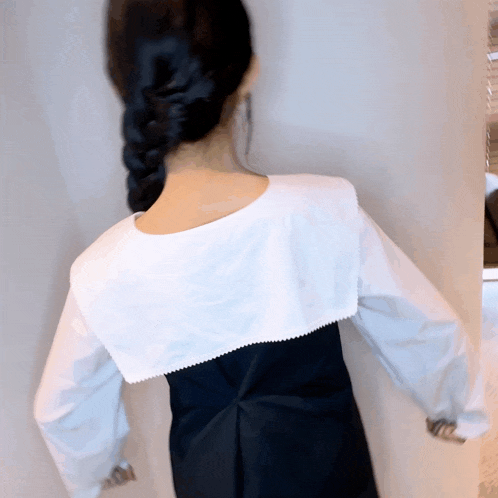 the back of a woman wearing a black dress and a white shirt