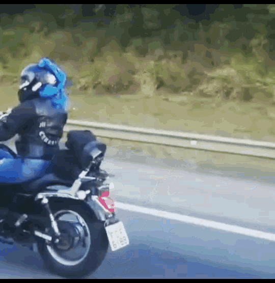a person riding a motorcycle on a highway with a license plate that says tcs 6185
