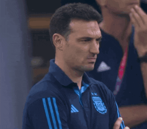 a man wearing a blue adidas shirt is looking at the camera